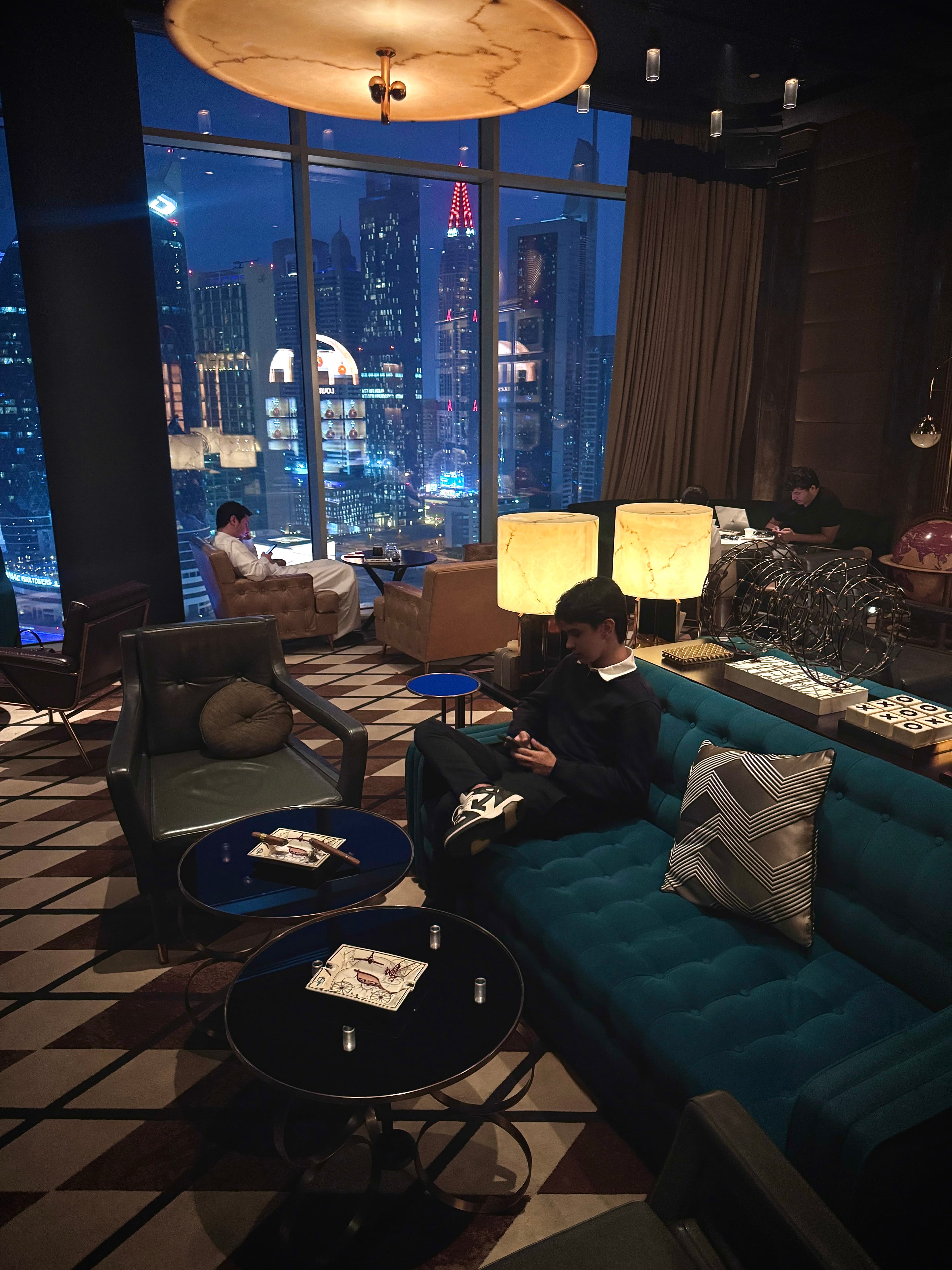 Arthur Oliveira em lounge sofisticado com vista para Dubai à noite